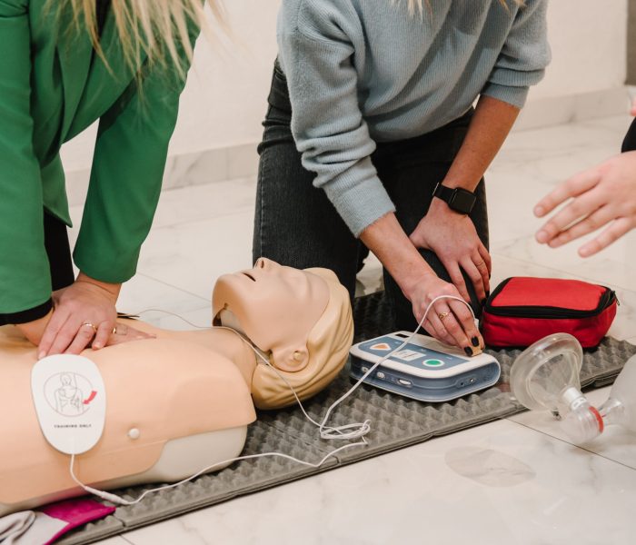 Automated external defibrillator device, AED with training dummy mannequin. Use an automatic defibrillator in conducting basic cardiopulmonary resuscitation of victim. Demonstrating chest compressions